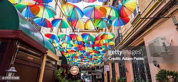 group of colourful umbrellas in narrow street, bucharest, romania - bucharest stock pictures, royalty-free photos & images
