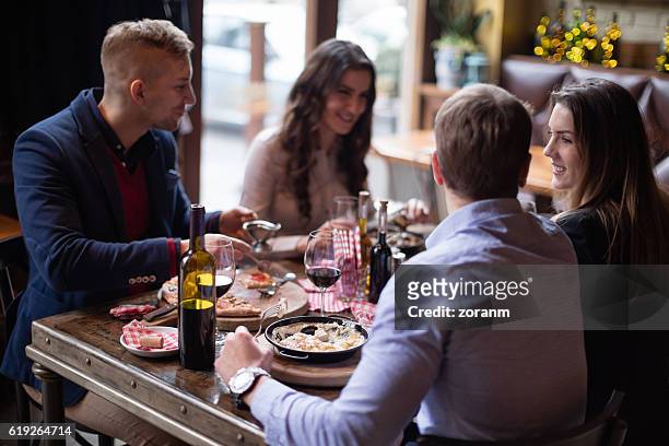 friends eating italian food in restaurant - parmesan cheese pizza stock pictures, royalty-free photos & images