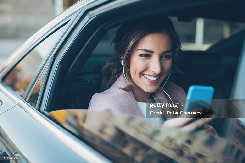 Femme avec téléphone sur le siège arrière d’une voiture