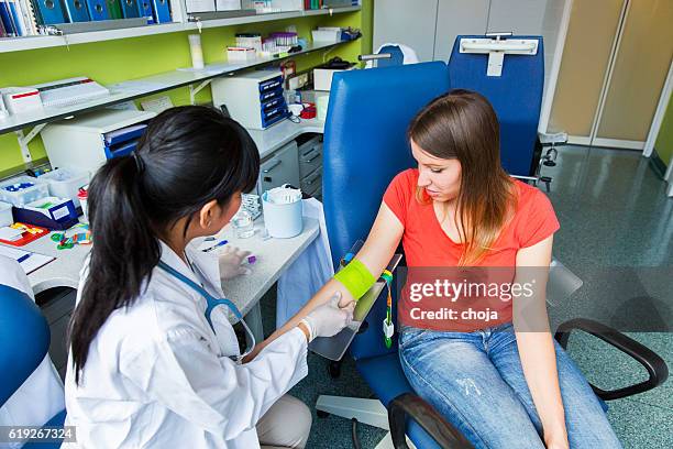 drawing blood...young doctor prepairing for blood capture - iv going into an arm stock pictures, royalty-free photos & images