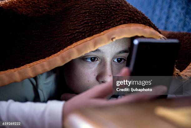 girl in bed texting on smartphone - child sadness stock pictures, royalty-free photos & images