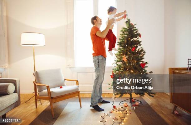 padre e figlio decorano l'albero di natale - decorare l'albero di natale foto e immagini stock