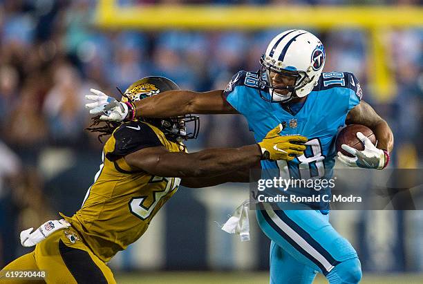 Wide receiver Rashad Greene of the Tennessee Titans carries the ball as Johnathan Cyprien of the Jacksonville Jaguars tries to tackle him during a...