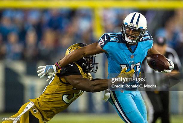 Wide receiver Rashad Greene of the Tennessee Titans carries the ball as Johnathan Cyprien of the Jacksonville Jaguars tries to tackle him during a...