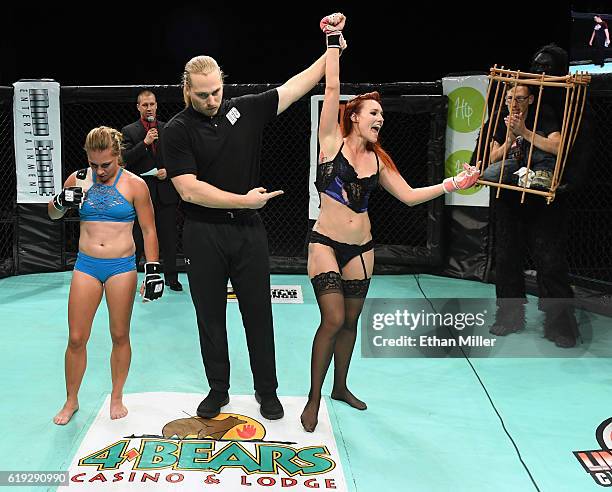 Fighter Andreea "The Storm" Vladoi looks on as referee Nick Nelson holds up the arm of fighter Jolene "The Valkyrie" Hexx after she won their bout as...