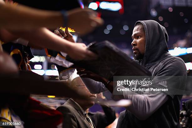 Kevin Durant of the Golden State Warriors signs autographs for fans before the NBA game against the Phoenix Suns at Talking Stick Resort Arena on...