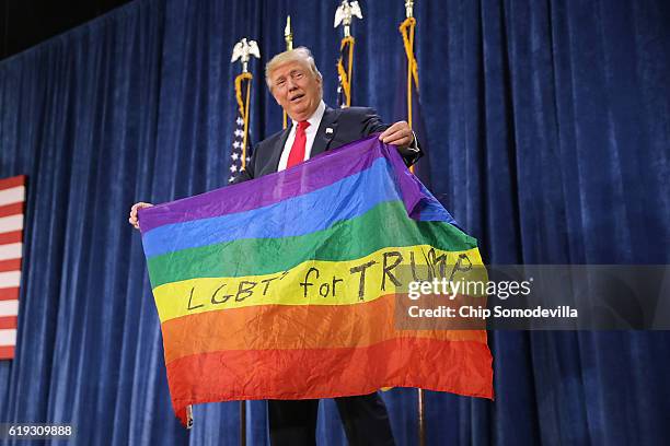 Republican presidential nominee Donald Trump holds an LGBT rainbow flag given to him by supporter Max Nowak during a campaign rally at the Bank of...