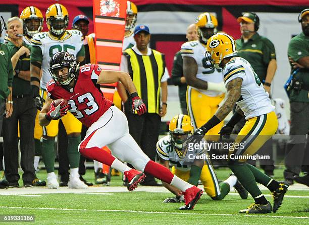 Jacob Tamme of the Atlanta Falcons runs with a catch against Morgan Burnett and LaDarius Gunter of the Green Bay Packers at the Georgia Dome on...