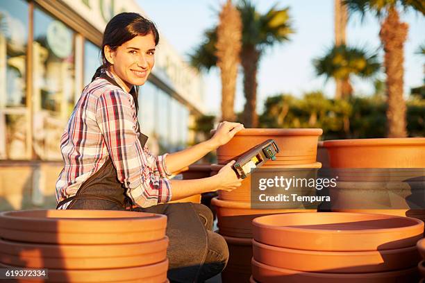 commis aux ventes utilisant le pistolet à prix sur les pots de fleurs. - étiqueter photos et images de collection
