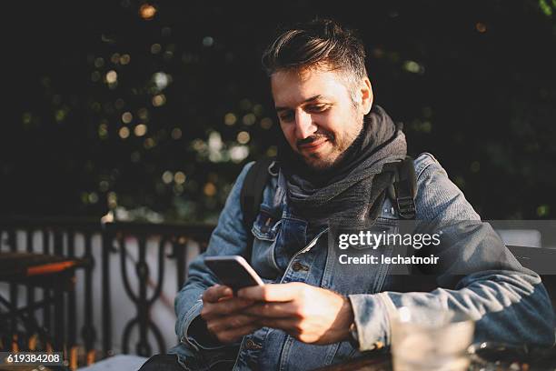 young man sitting in a cafe in berlin prenzlauer berg - denim jacket stock pictures, royalty-free photos & images