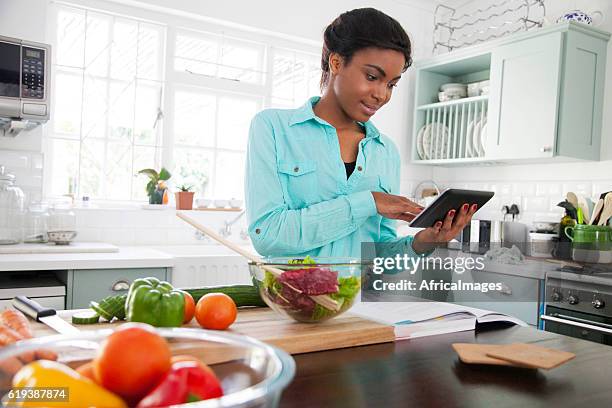 african woman reading a recipe. - meal planning stock pictures, royalty-free photos & images