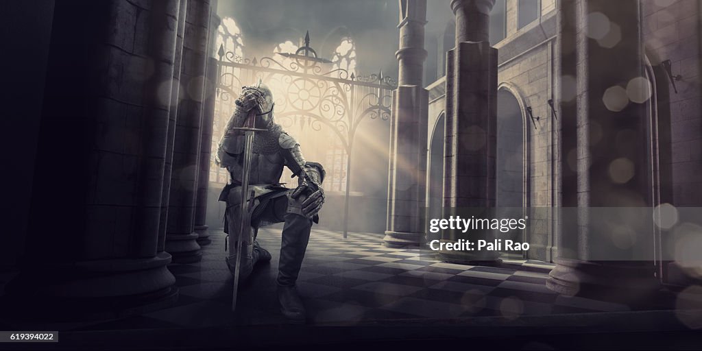 Medieval Knight in Armour Kneeling With Sword Inside Castle