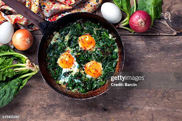 espinacas estofadas y huevos en una vieja sartén - espinaca fotografías e imágenes de stock