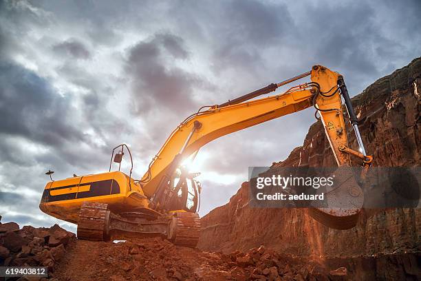 erdarbeiten mit dramatischem himmel - raupenfahrwerk stock-fotos und bilder