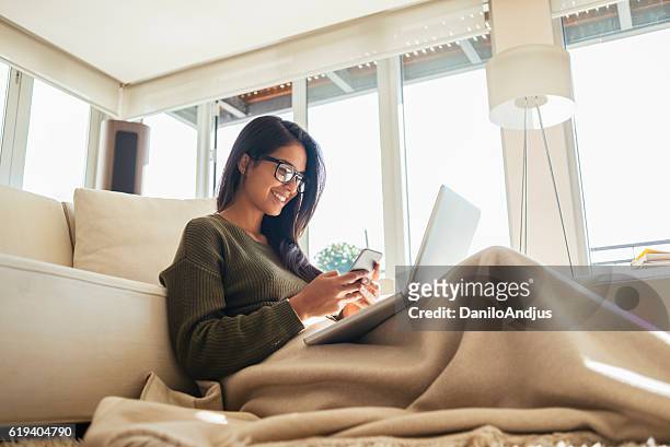 giovane donna che usa il suo smartphone e laptop - girl looking at computer foto e immagini stock