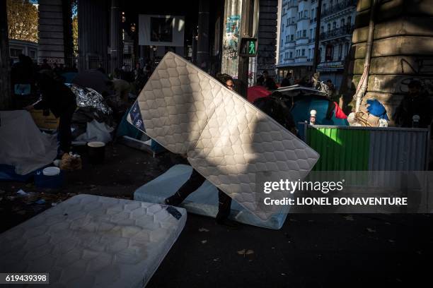 Migrant carries a mattress at a makeshift camp at the Boulevard de la Villette, near the Jaures and Stalingrad metro stations, in northern Paris on...