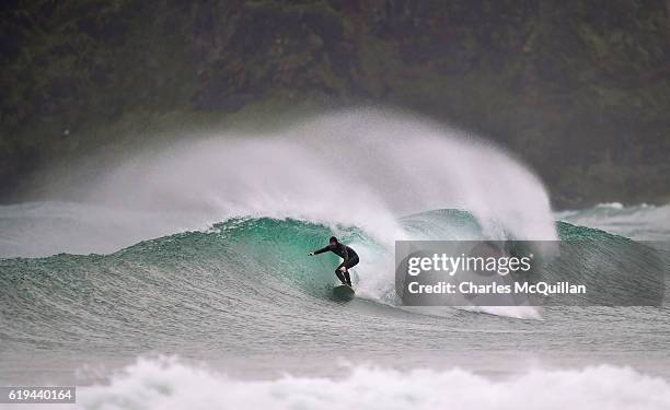 Professional surfer Al Mennie catches a wave under the historic Dunluce Castle ruins on October 31, 2016 in Portrush, Northern Ireland. Built in the...