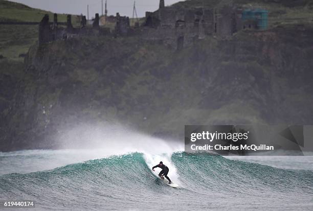 Professional surfer Al Mennie catches a wave under the historic Dunluce Castle ruins on October 31, 2016 in Portrush, Northern Ireland. Built in the...