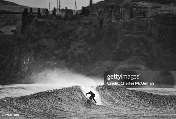 Professional surfer Al Mennie catches a wave under the historic Dunluce Castle ruins on October 31, 2016 in Portrush, Northern Ireland. Built in the...