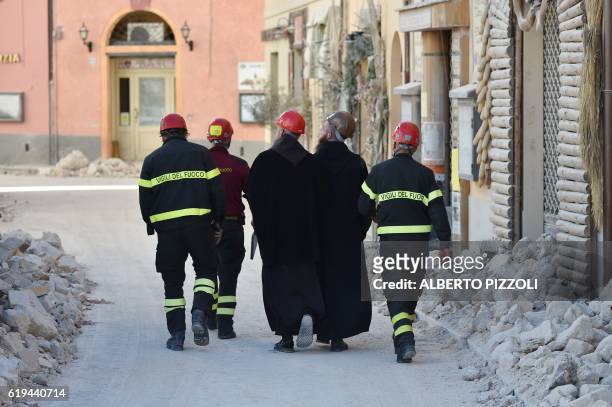 Firefighters escort monks in the historic center of Norcia, on October 31 a day after a 6.6 magnitude earthquake hit central Italy. It came four days...