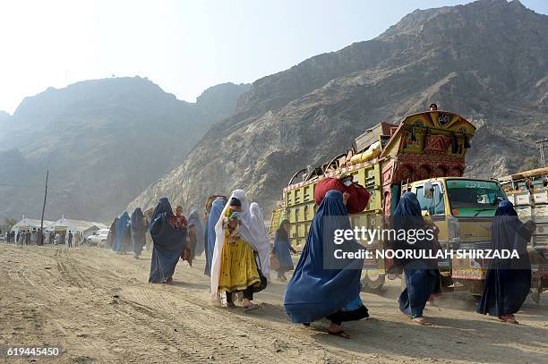 Burqa-clad Afghan refugees arrive at the United Nations High Commissioner for Refugees repatriation center in Torkham, as they cross through the main...