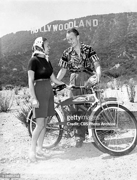 Les Tremayne, of CBS Radio's "First Nighter" program, and wife , with their bicycles in the Hollywood Hills, with the Hollywoodland sign in the...