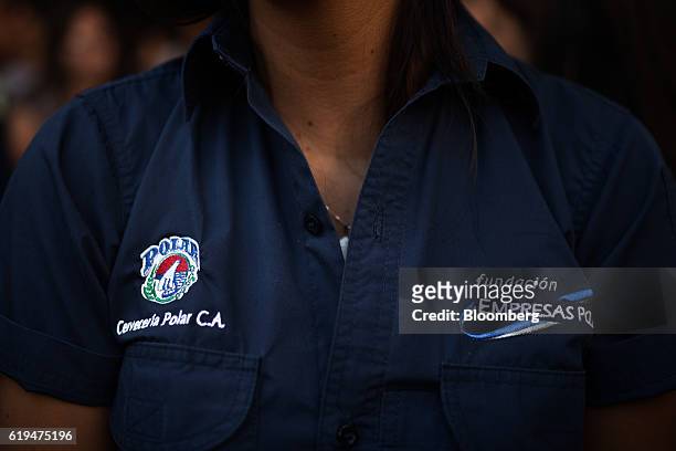 Signage for Empresas Polar SA is displayed on an employee's shirt listen during a news conference outside the company's headquarters in Caracas,...