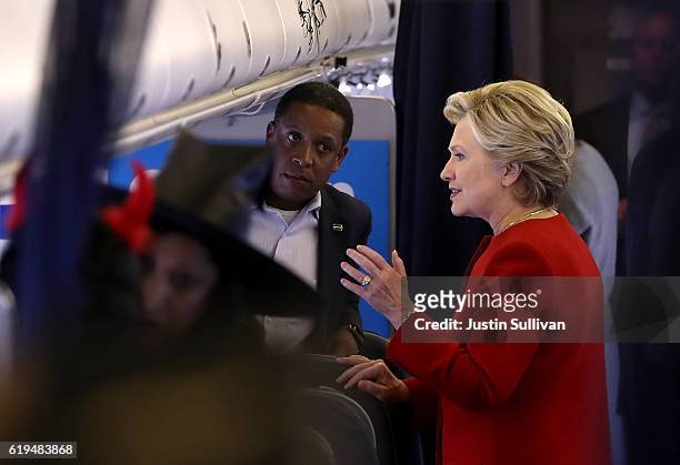 Democratic presidential nominee former Secretary of State Hillary Clinton talks with campaign advisor Darren Peters aboard her campaign plane at...