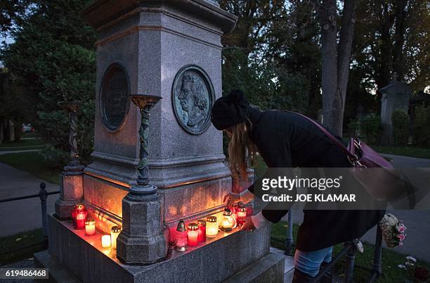 Woman lights a candle at the memorial of Wolfgang Amadeus Mozart at Vienna's Central Cemetery on the eve of All Saints Day in Vienna, Austria on...