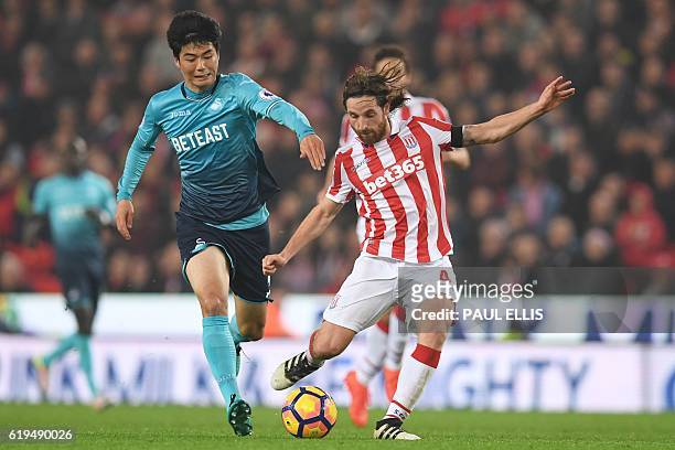 Swansea City's South Korean midfielder Ki Sung-Yueng vies with Stoke City's Welsh midfielder Joe Allen during the English Premier League football...