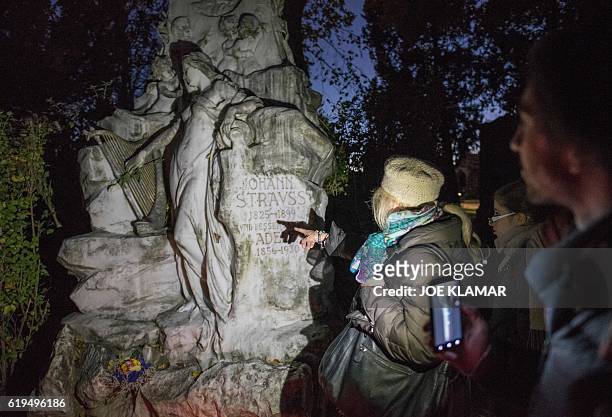 Visitors look at a grave of composer Johann Strauss at Vienna's Central Cemetery on the eve of All Saints Day in Vienna, Austria on October 31, 2016....
