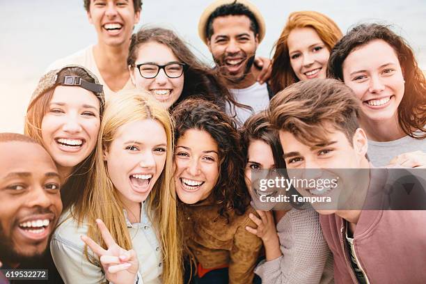 retrato de un gran grupo de amigos en la playa - group a fotografías e imágenes de stock