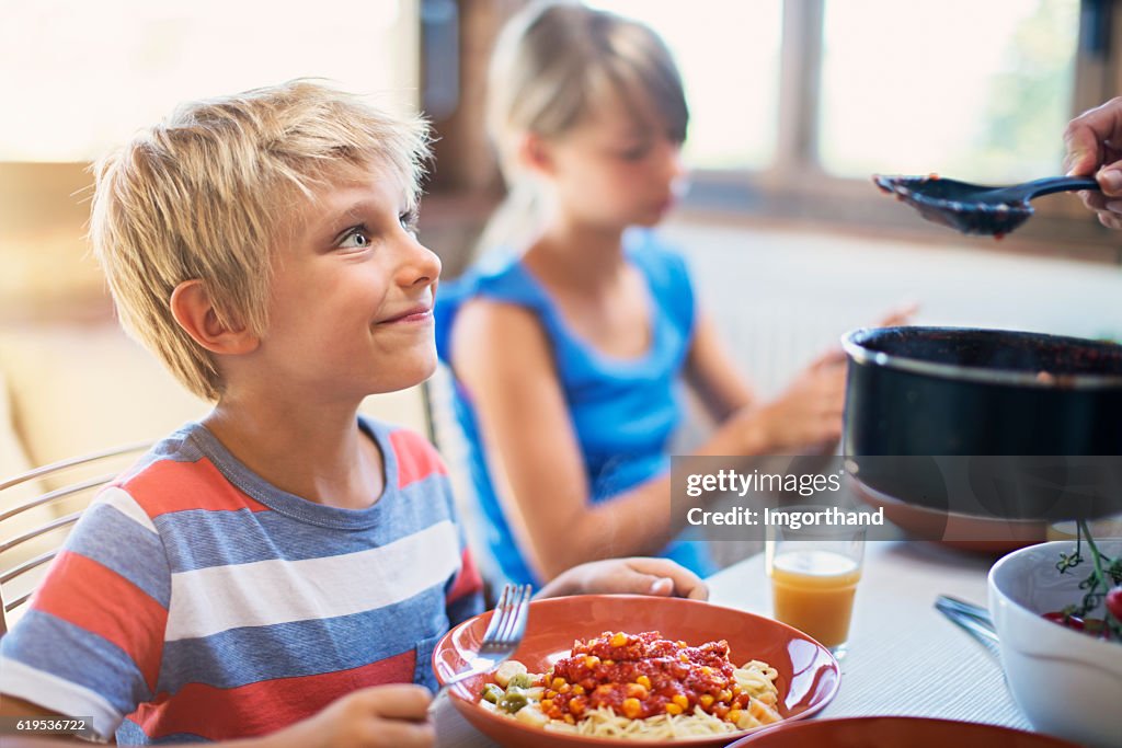 Happy kids enjoying delicious pasta meal