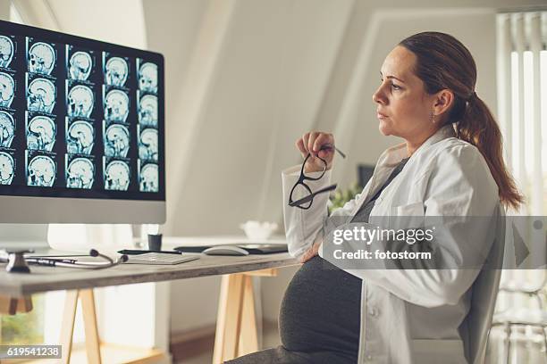 pregnant female doctor examining brain scan - mri abdomen stock pictures, royalty-free photos & images