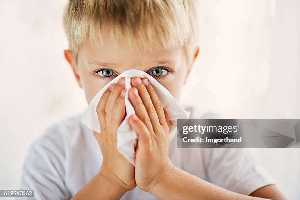 sick little boy cleaning his runny nose. - blowing nose stock pictures, royalty-free photos & images