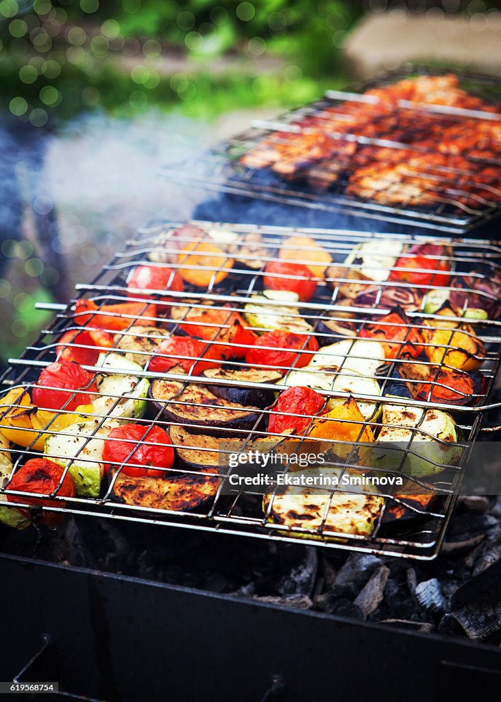Close up of grilled vegetables on grate and shashliks on fire