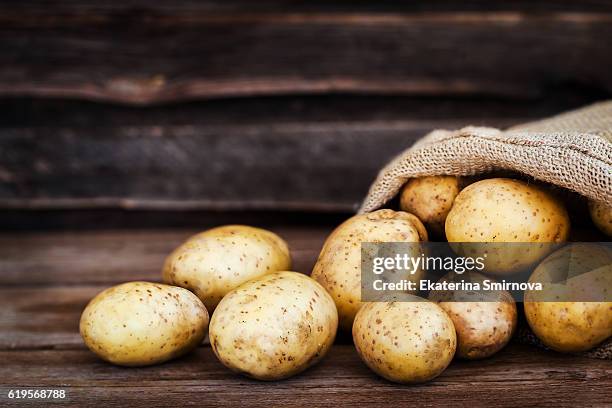 raw fresh potatoes in the sack on wooden background - raw potato stock pictures, royalty-free photos & images