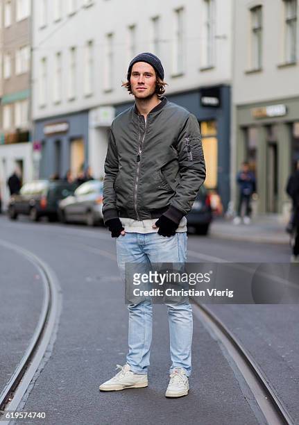 Philipp Grassinger wears an olive bomber jacket, wool hat, black fingerless gloves, light blue washed denim jeans, white sneaker on October 31, 2016...