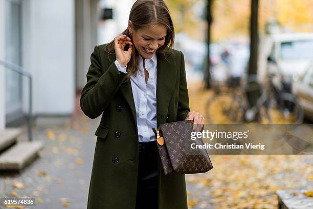 Julia Isabella Kuhne wears a khaki coat from Ivy & Oak, white blouse from H&M Trend, black pants from ZARA, Louis Vuitton bag clutch on October 31,...