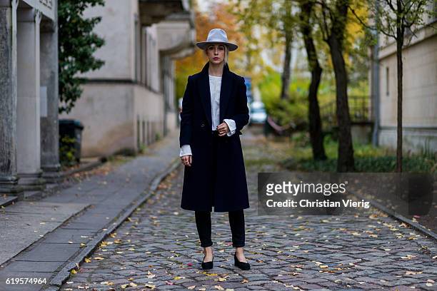 Leonie Markhorst wears a navy vintage coat, white top Oak + Fort, black skinny jeans COS, black shoes from Oak + Fort, grey hat from Lack of Color on...