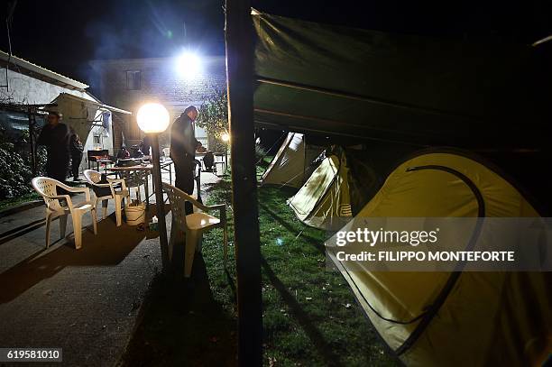 Famly stands in the garden of their house where they set up tents in Cascia on October 31 a day after a 6.6 magnitude earthquake hit central Italy....