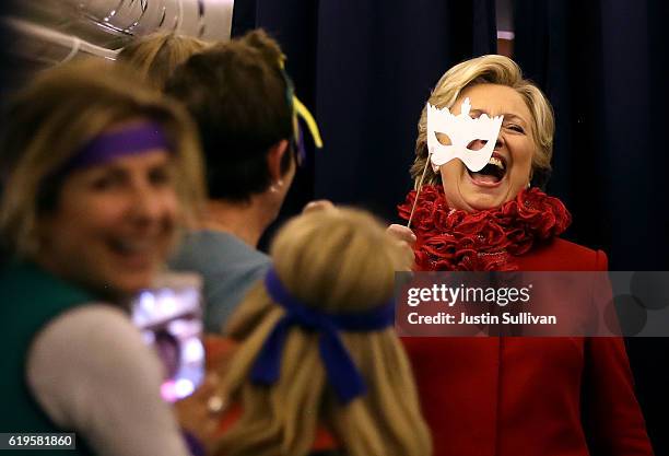 Democratic presidential nominee Hillary Clinton holds a masquerade mask as she jokes with members of her staff aboard her camapign plane on October...