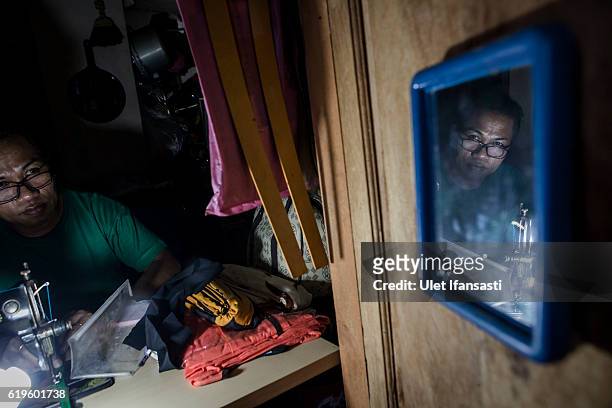 Transvestite Yanti , sewing a cloth inside her house, Yanti has joined the group for 22 years in a traditional dance opera group called Ludruk Karya...