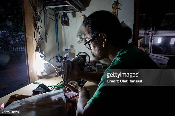 Transvestite Yanti , sewing a cloth inside her house, Yanti has joined the group for 22 years in a traditional dance opera group called Ludruk Karya...