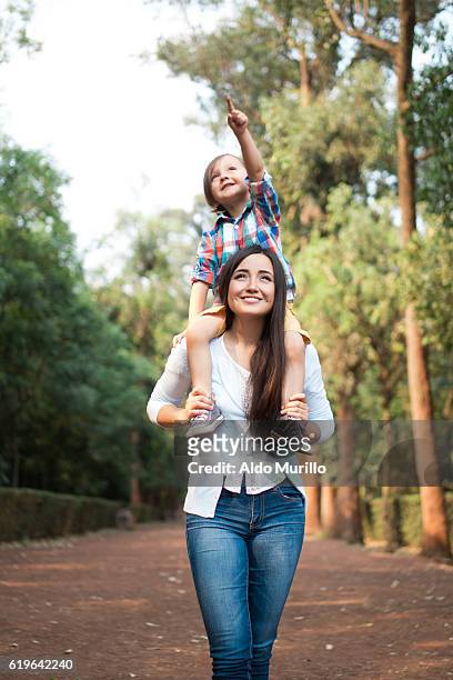young mother carrying son on shoulders and looking away - child on shoulders stockfoto's en -beelden