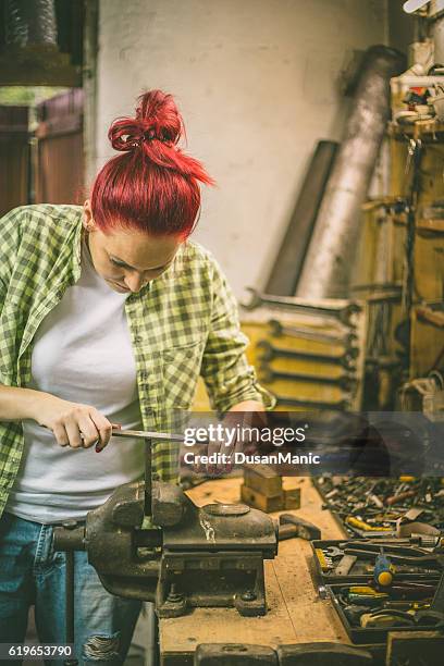 busy woman tinkering in workshop. - metal sanding stockfoto's en -beelden