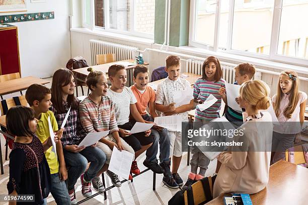 above view of teacher singing with children during music lesson. - choir imagens e fotografias de stock