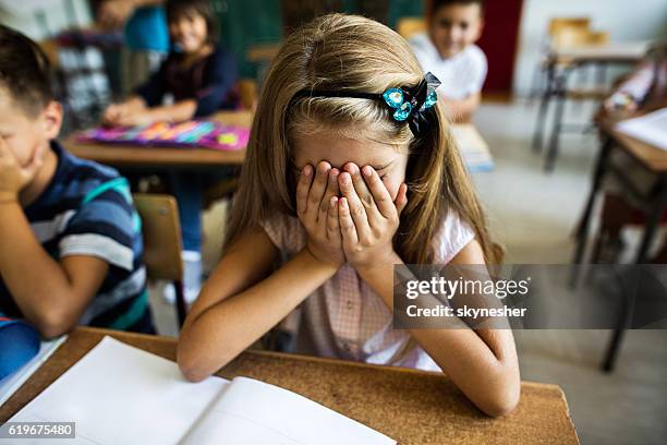 sad schoolgirl holding her head in hands in the classroom. - face covered stock pictures, royalty-free photos & images