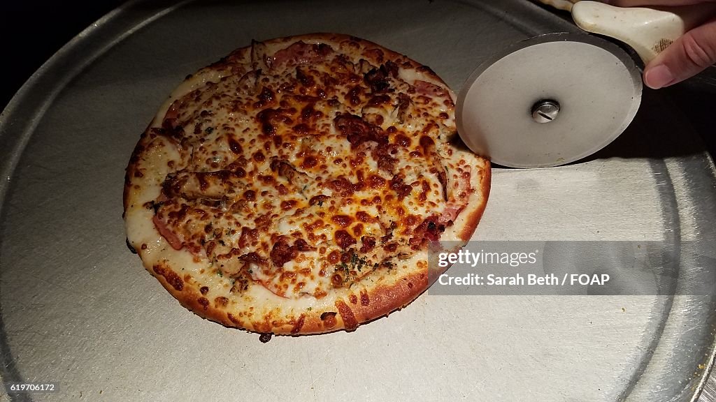 Person hand cutting pizza