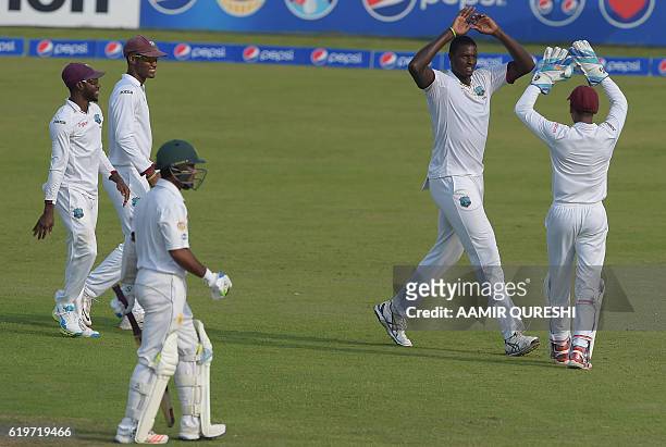 West Indies' cricket captain Jason Holder celebrates with teammates after taking the wicket of Pakistani batsman Asad Shafiq on the third day of the...